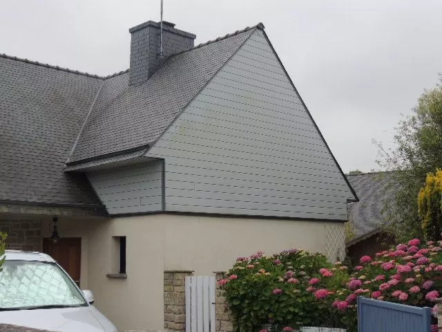 Maison avec toit métallique et jardin fleuri.