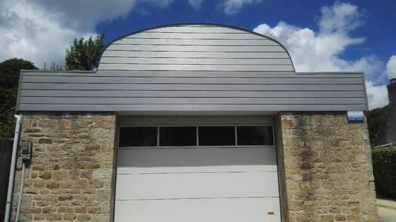 Garage avec toit métallique courbé, travaux en cours.