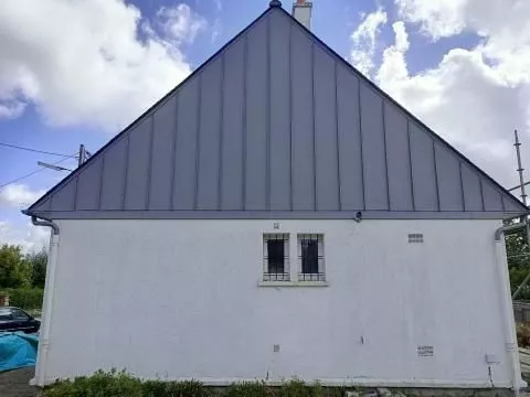Toit métallique sur une maison avec fenêtres en toiture.