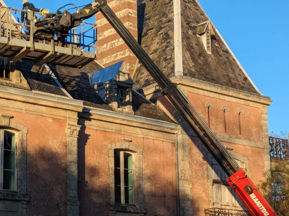 Rénovation de toit avec un équipement de levage, travail sur un toit en pente.
