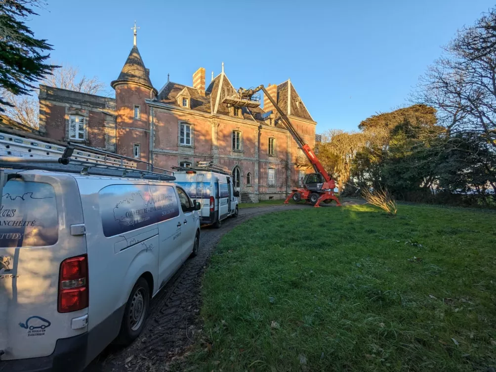 Rénovation d’un toit de manoir, équipe de travail et véhicule présents sur le site.