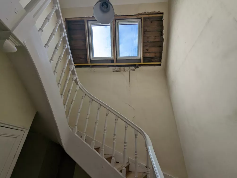 Vue intérieure d’un escalier avec fenêtre de toit et lumière naturelle.